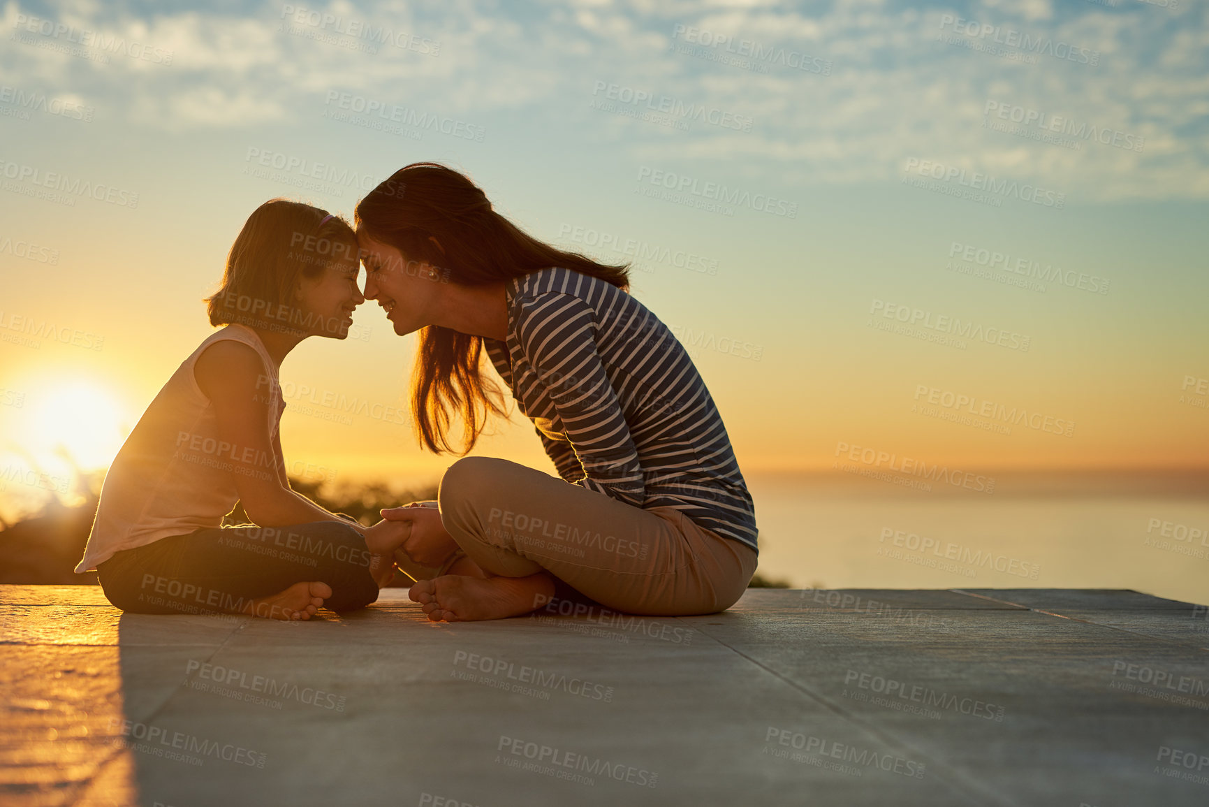 Buy stock photo Silhouetted shot of a mother and daughter bonding outside at sunset
