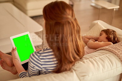 Buy stock photo Shot of a mother using her tablet at home while her daughter sleeps