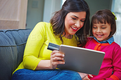 Buy stock photo Shot of a mother and daughter using a credit card with a tablet at home