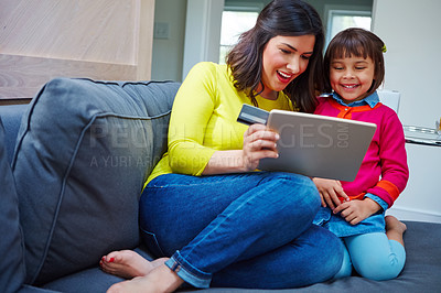 Buy stock photo Shot of a mother and daughter using a credit card with a tablet at home