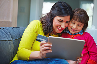 Buy stock photo Shot of a mother and daughter using a credit card with a tablet at home