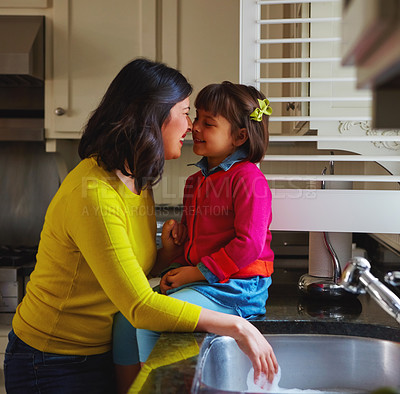 Buy stock photo Shot of a young mother and her daughter bonding by the kitchen sink