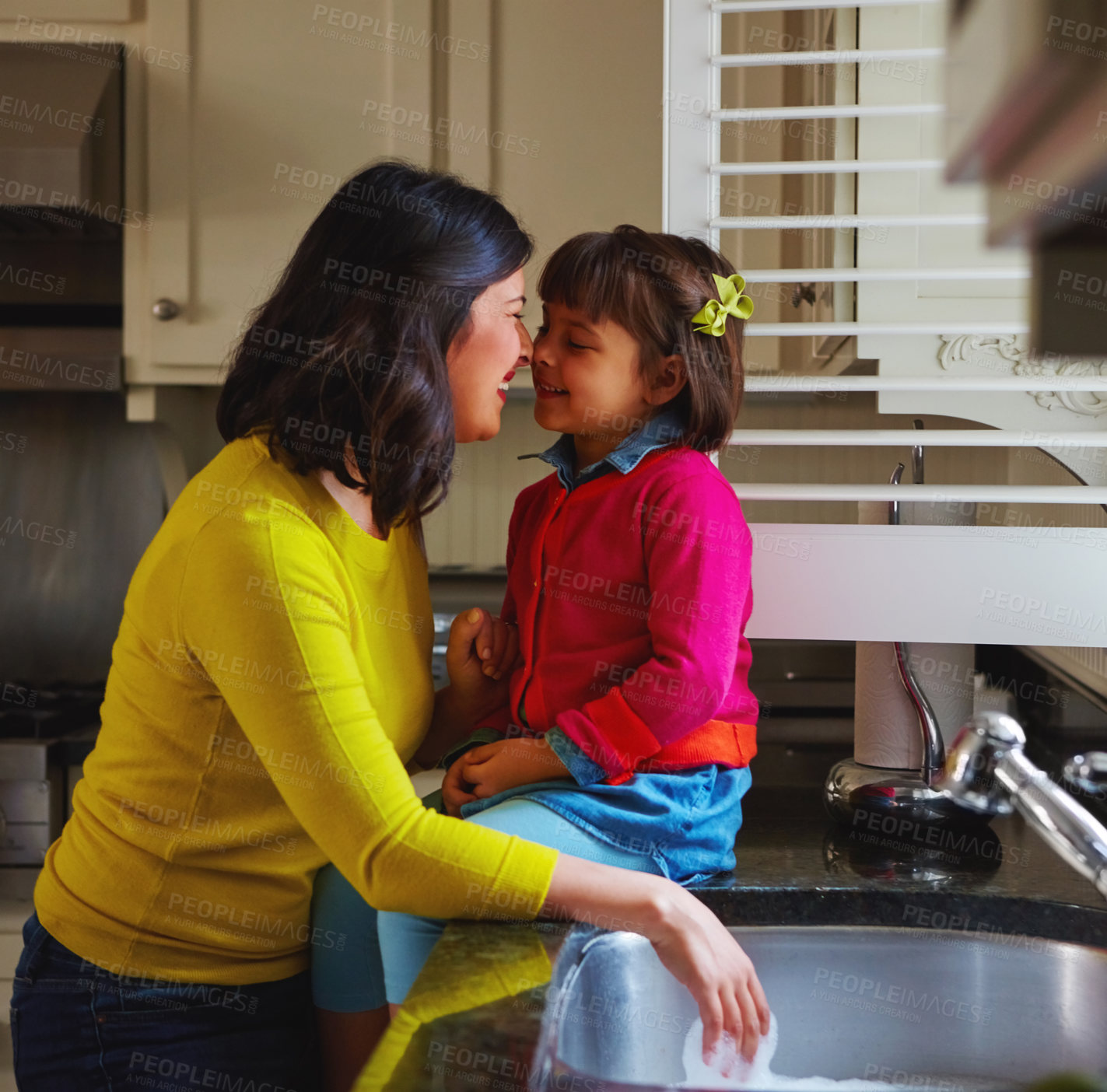Buy stock photo Shot of a young mother and her daughter bonding by the kitchen sink