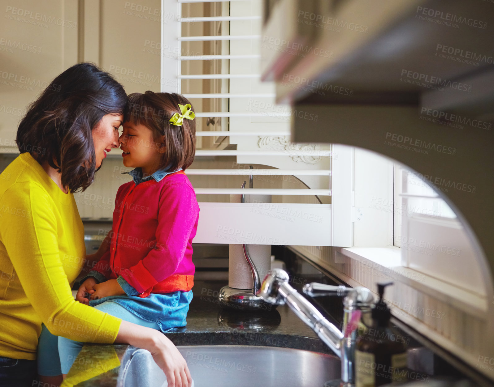 Buy stock photo Shot of a young mother and her daughter bonding by the kitchen sink