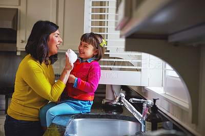 Buy stock photo Shot of a young mother and her daughter playing by the kitchen sink