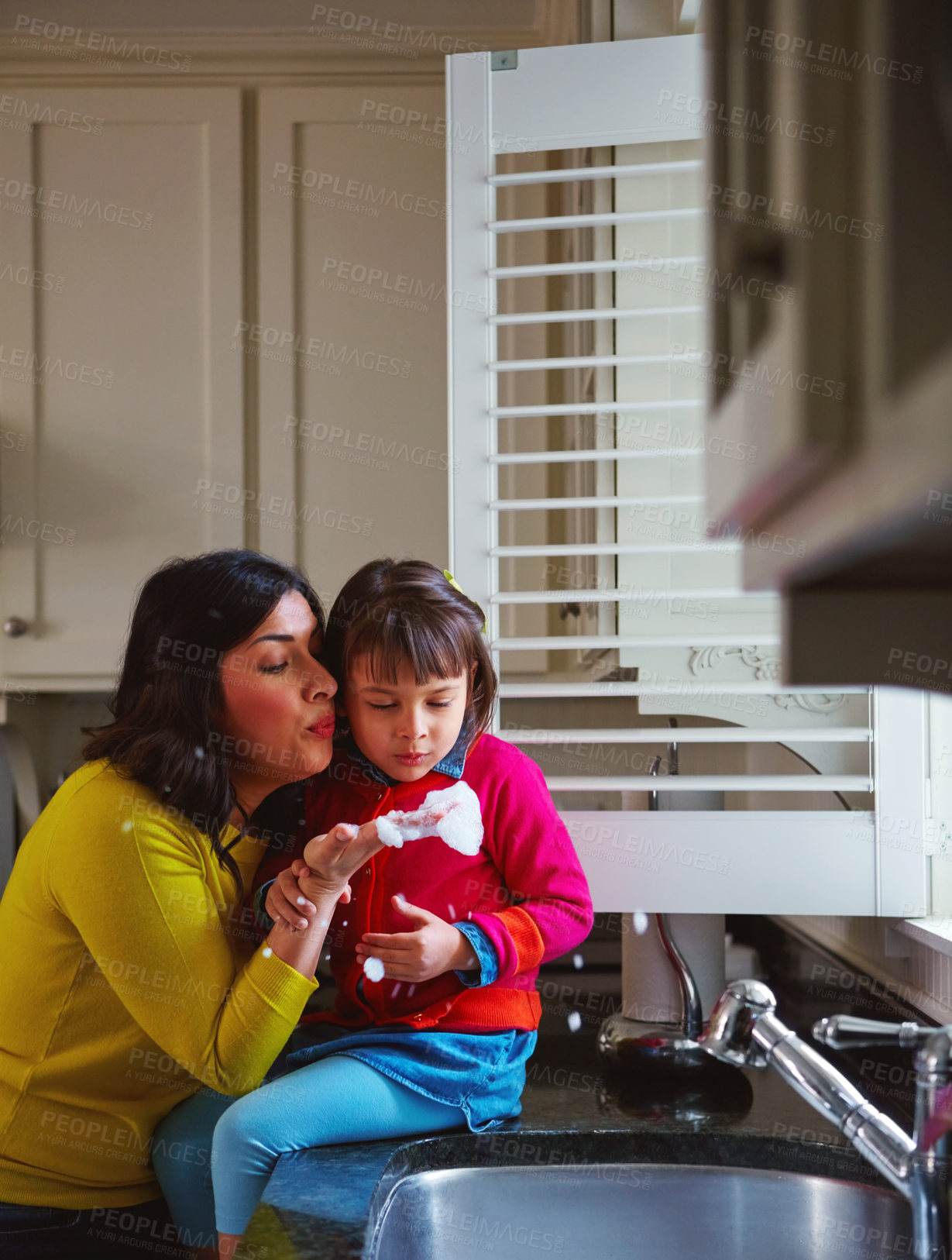 Buy stock photo Shot of a young mother and her daughter playing by the kitchen sink