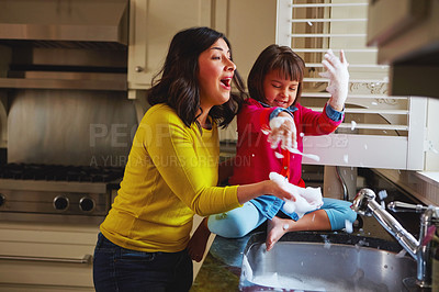 Buy stock photo Shot of a young mother and her daughter playing by the kitchen sink