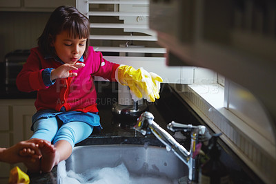 Buy stock photo Shot of a little girl playing with bubbles in a kitchen sink