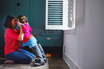 Buy stock photo Full length shot of a mother helping her daughter try on a pair of large rain boots t home