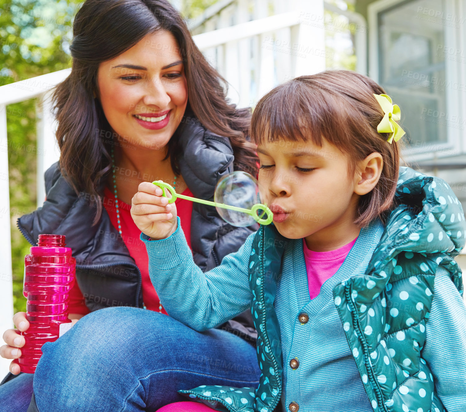 Buy stock photo Cropped shot of a mother watching her daughter blow bubbles outside