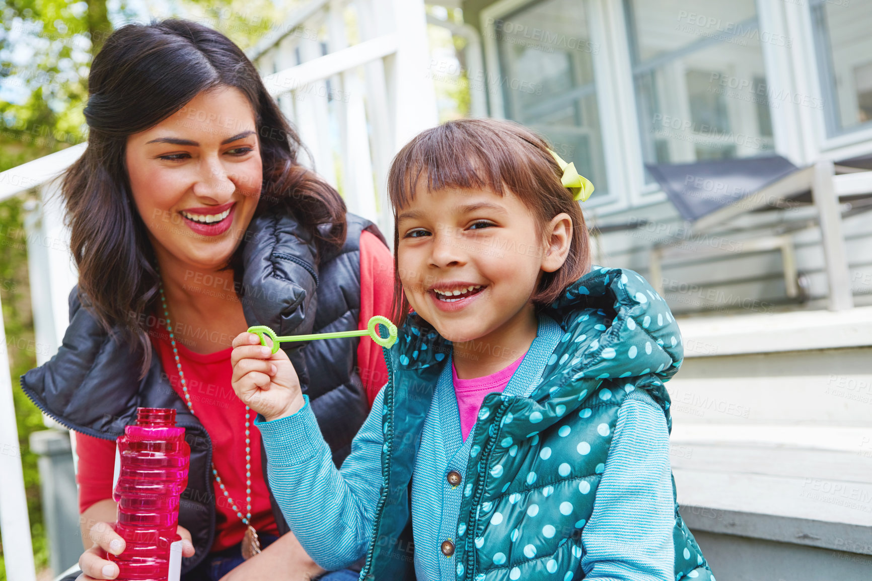 Buy stock photo Cropped shot of a mother watching her daughter blow bubbles outside