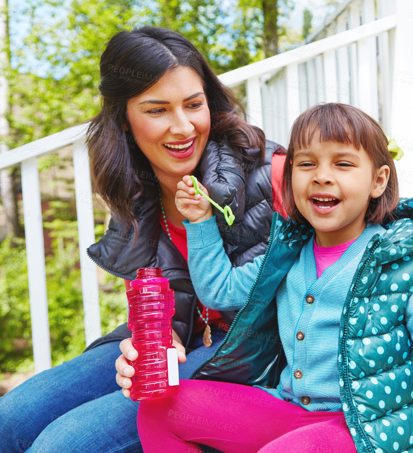 Buy stock photo Cropped shot of a mother watching her daughter blow bubbles outside