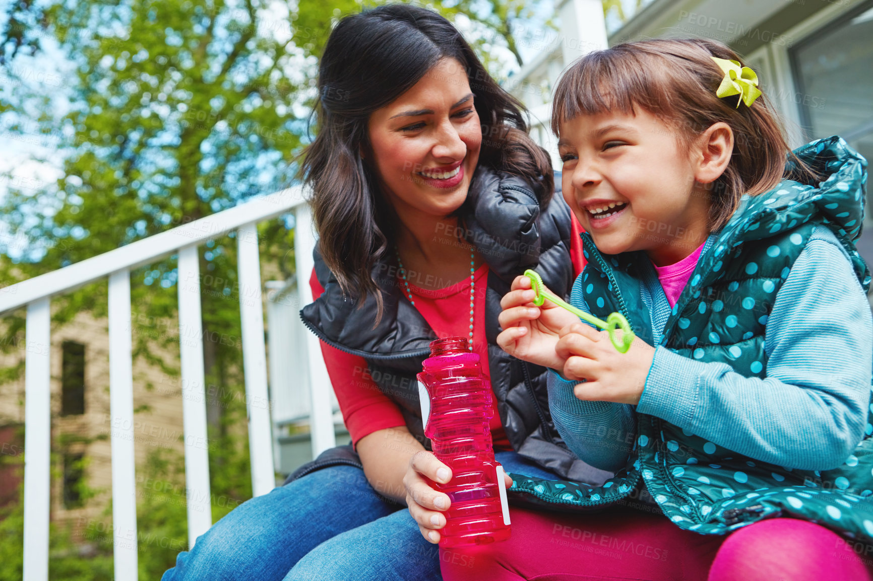 Buy stock photo Cropped shot of a mother watching her daughter blow bubbles outside