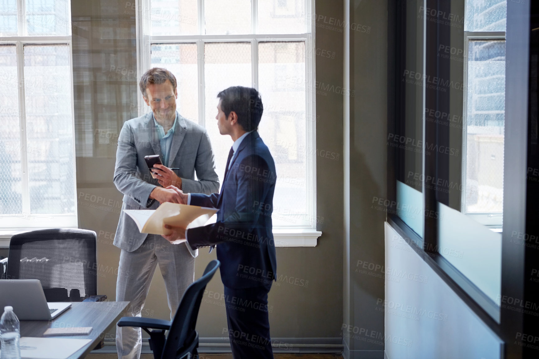 Buy stock photo Cropped shot of two businessmen shaking hands in the office