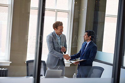 Buy stock photo Cropped shot of two businessmen shaking hands in the office