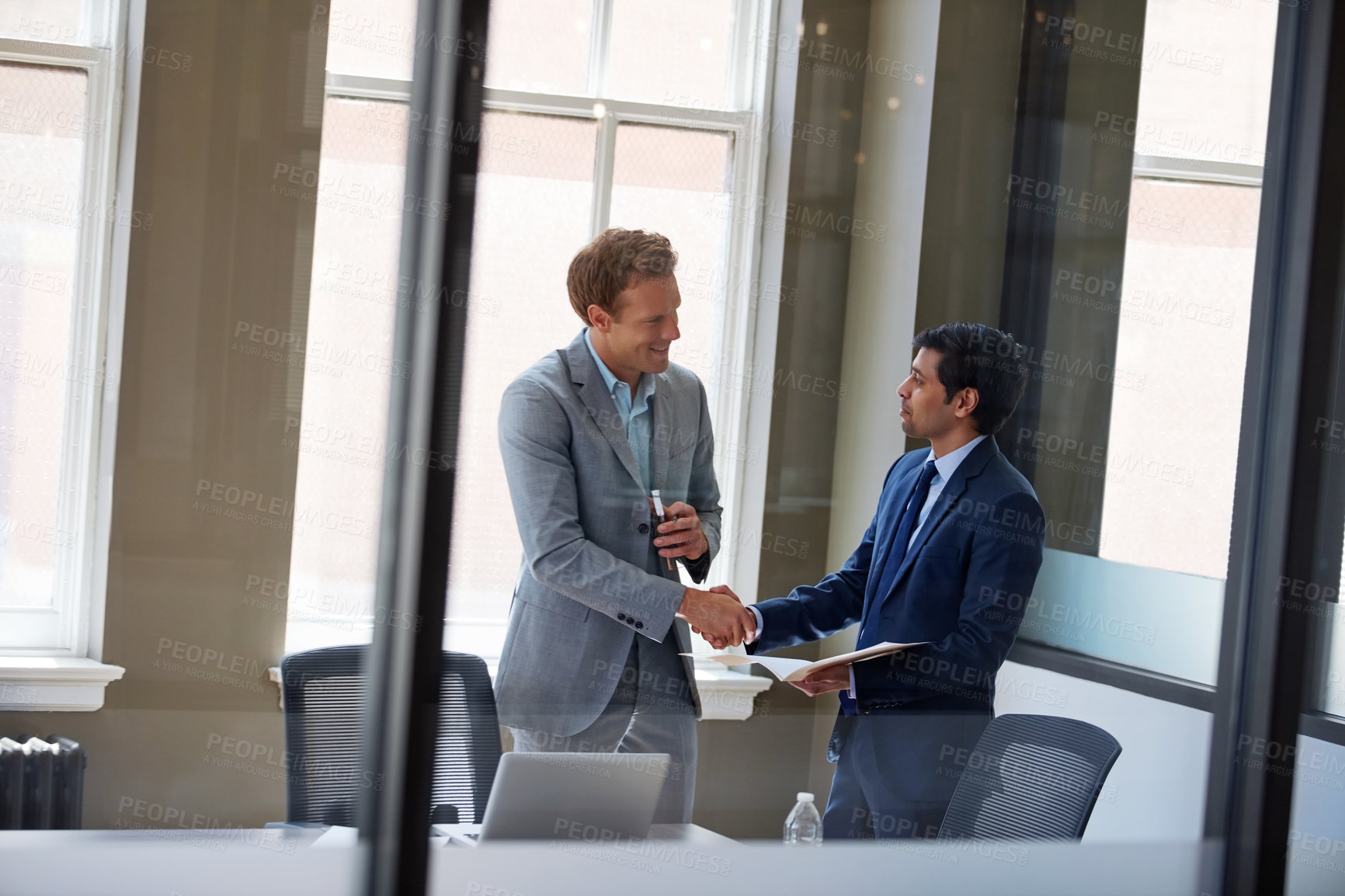 Buy stock photo Cropped shot of two businessmen shaking hands in the office