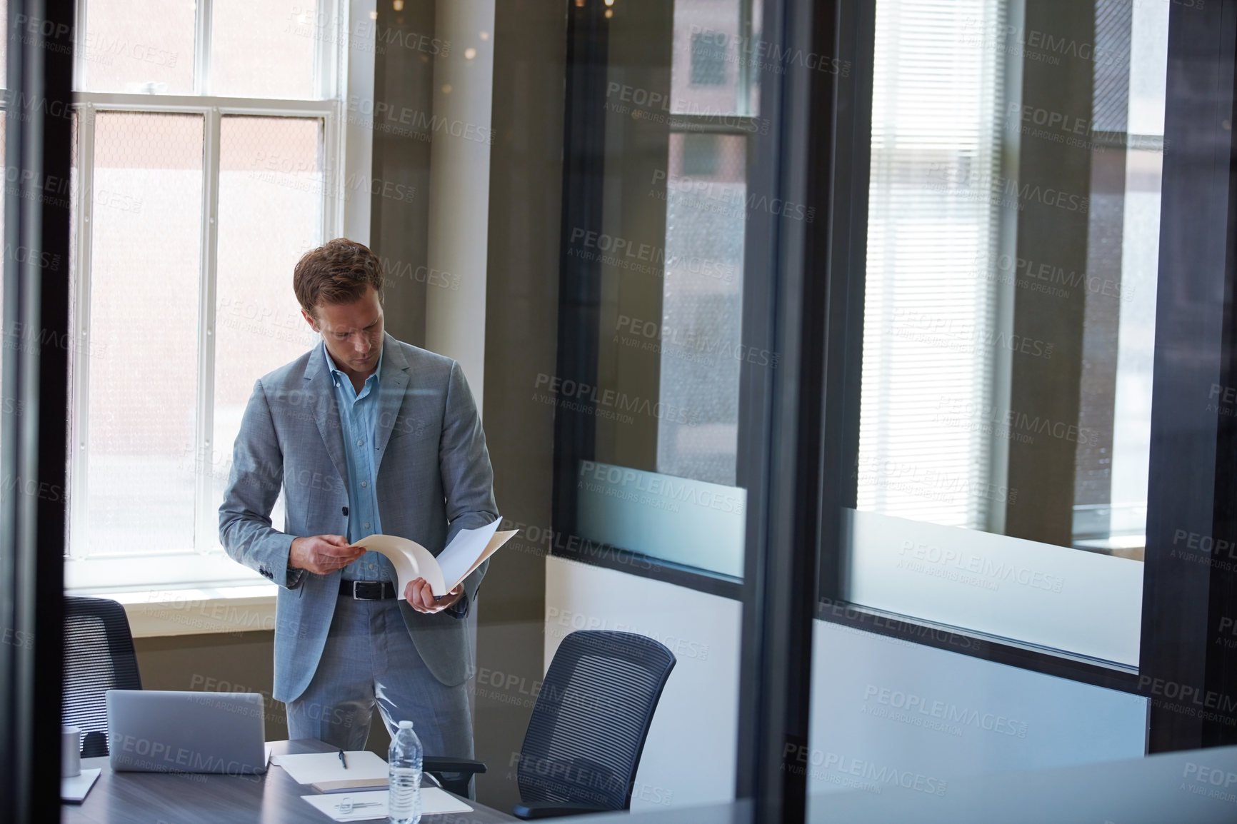 Buy stock photo Cropped shot of a businessman looking at paperwork in his office