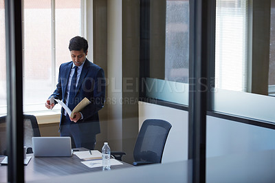 Buy stock photo Cropped shot of a businessman looking at paperwork in his office