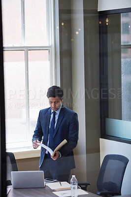 Buy stock photo Cropped shot of a businessman looking at paperwork in his office