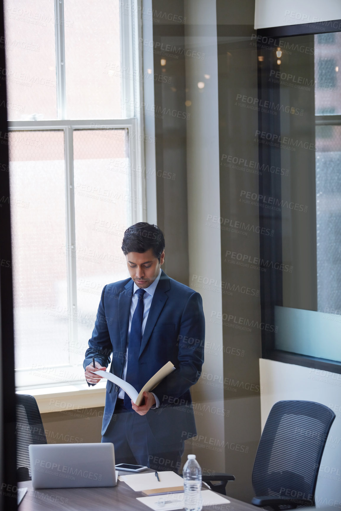 Buy stock photo Cropped shot of a businessman looking at paperwork in his office