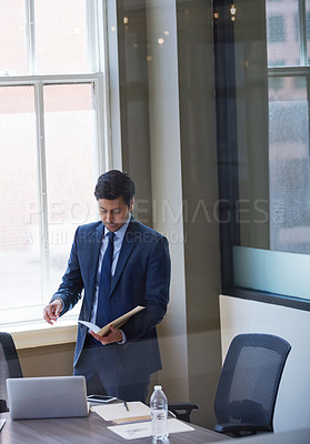 Buy stock photo Cropped shot of a businessman looking at paperwork in his office