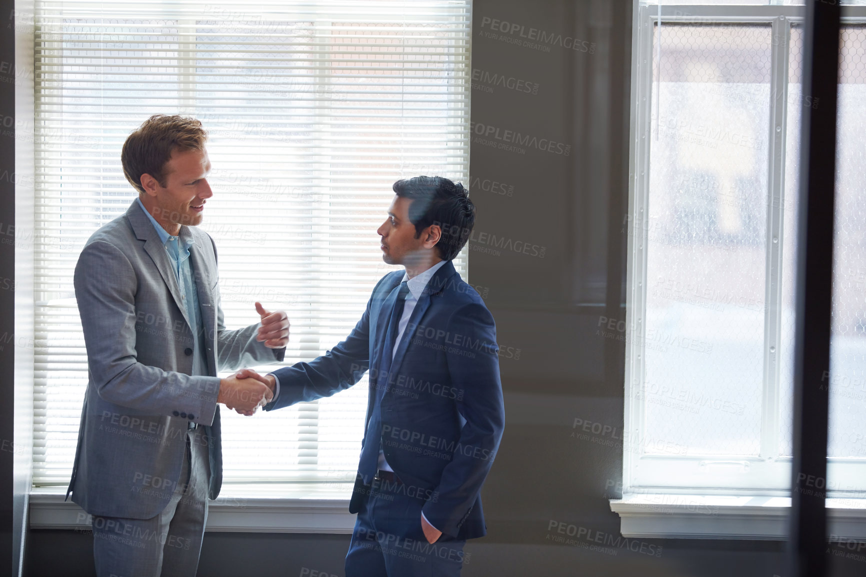 Buy stock photo Cropped shot of two businessmen shaking hands in the office