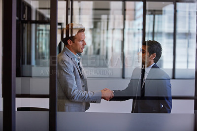 Buy stock photo Cropped shot of two businessmen shaking hands in the office