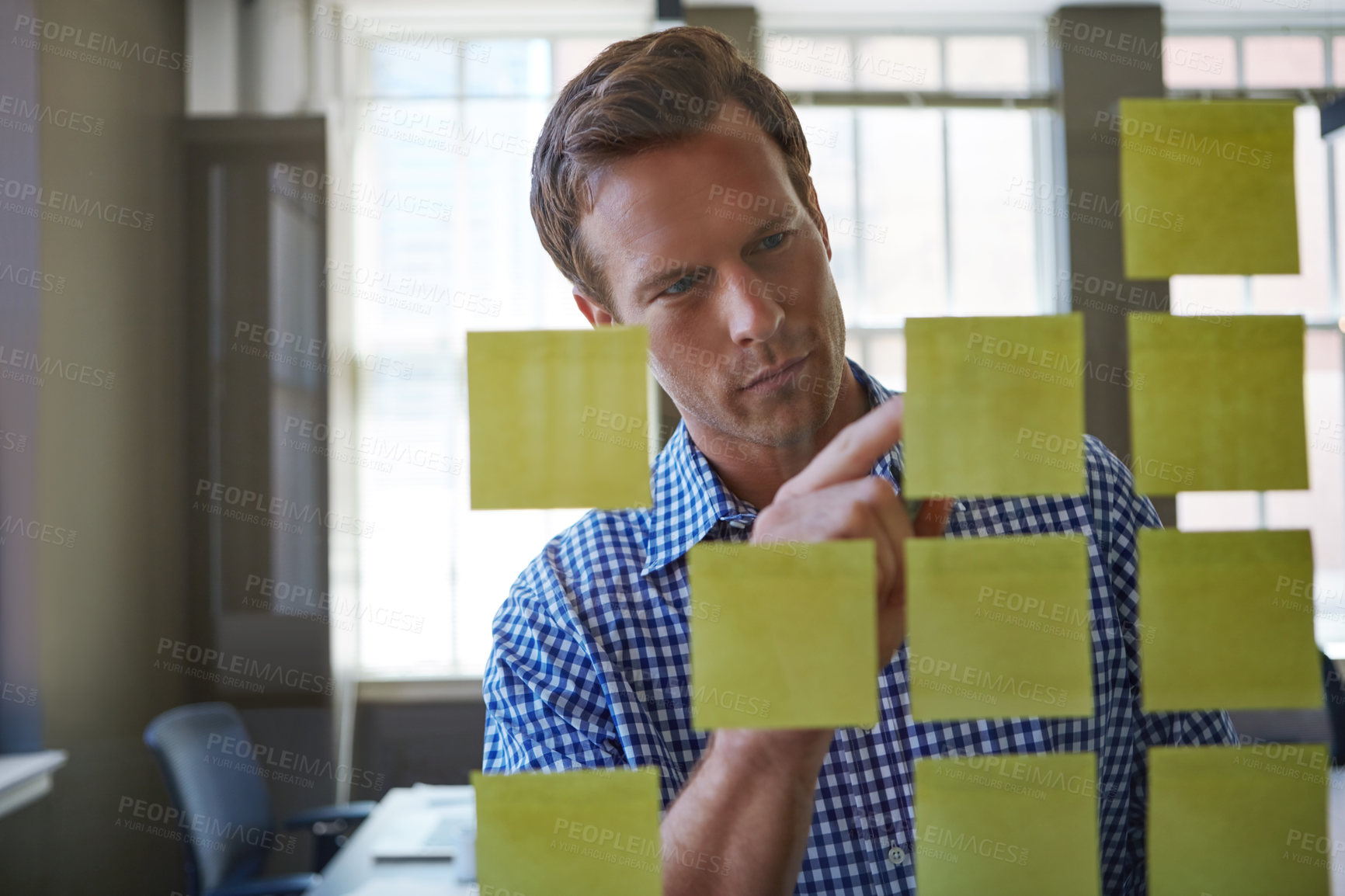 Buy stock photo Cropped shot of a handsome businessman arranging adhesive notes on a glass pane