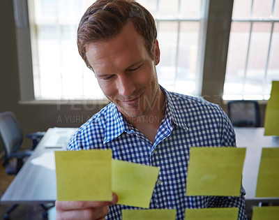 Buy stock photo Cropped shot of a handsome businessman arranging adhesive notes on a glass pane