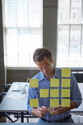 Buy stock photo Cropped shot of a handsome businessman arranging adhesive notes on a glass pane