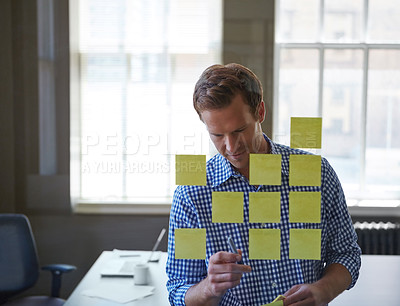 Buy stock photo Cropped shot of a handsome businessman arranging adhesive notes on a glass pane