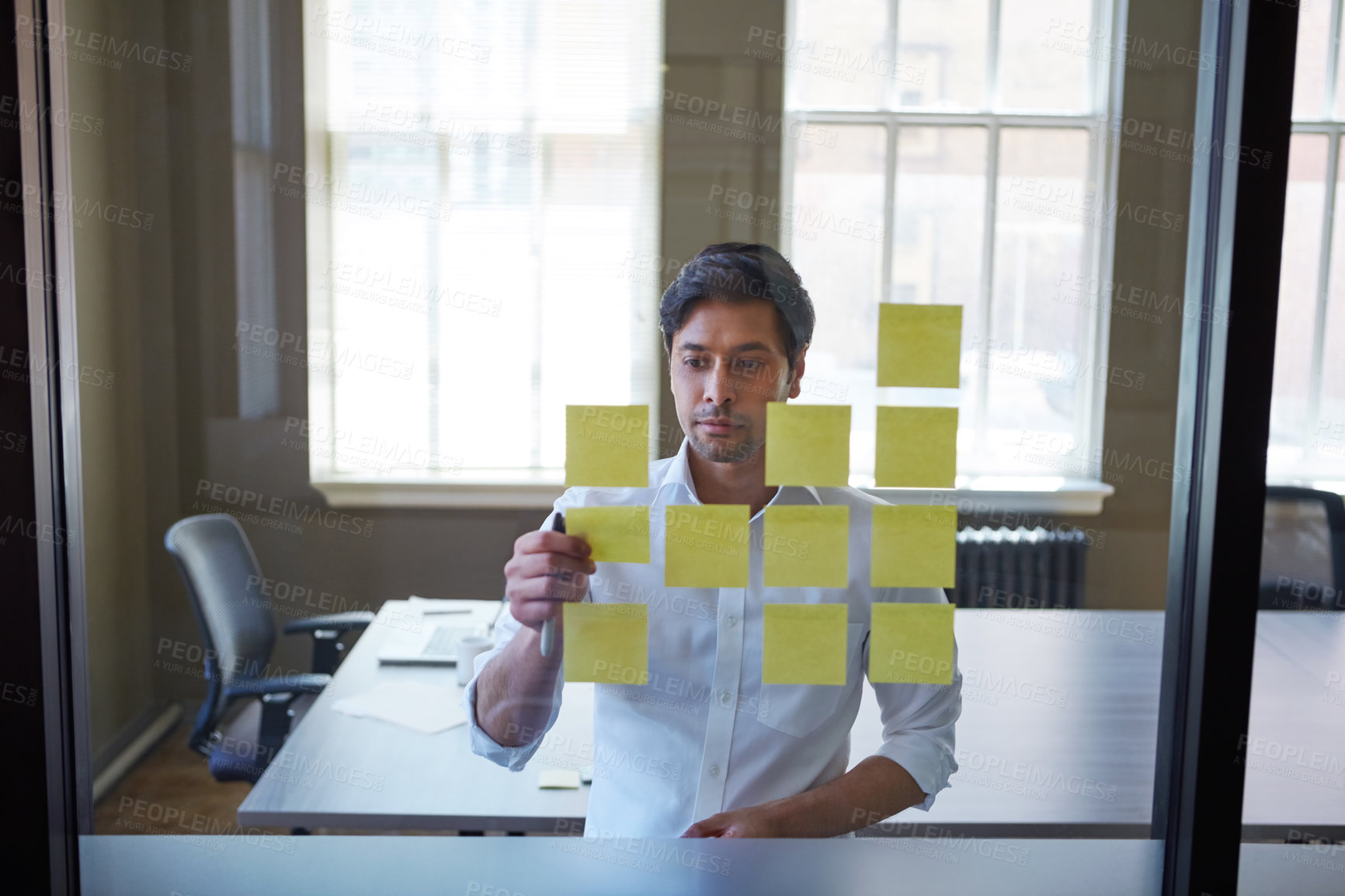 Buy stock photo Cropped shot of a handsome businessman arranging adhesive notes on a glass pane