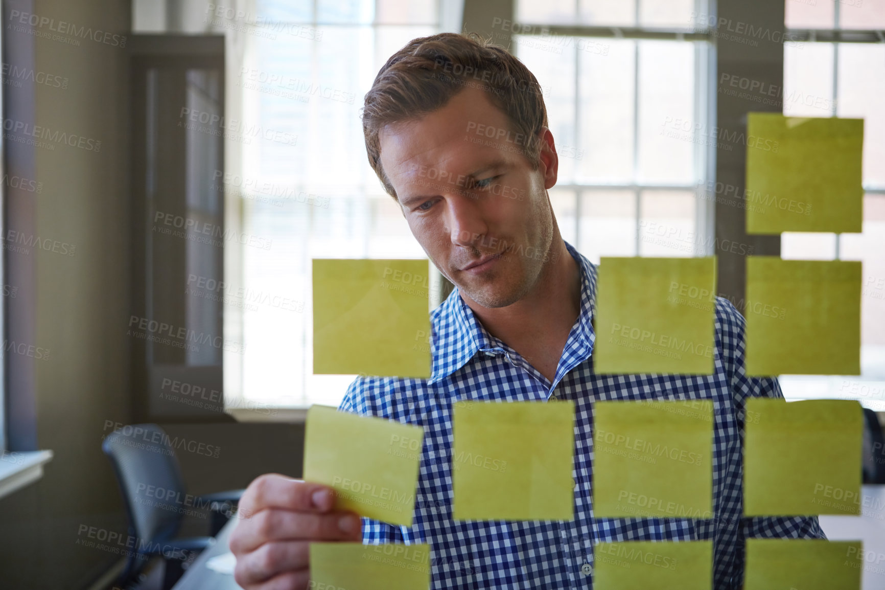 Buy stock photo Cropped shot of a handsome businessman arranging adhesive notes on a glass pane