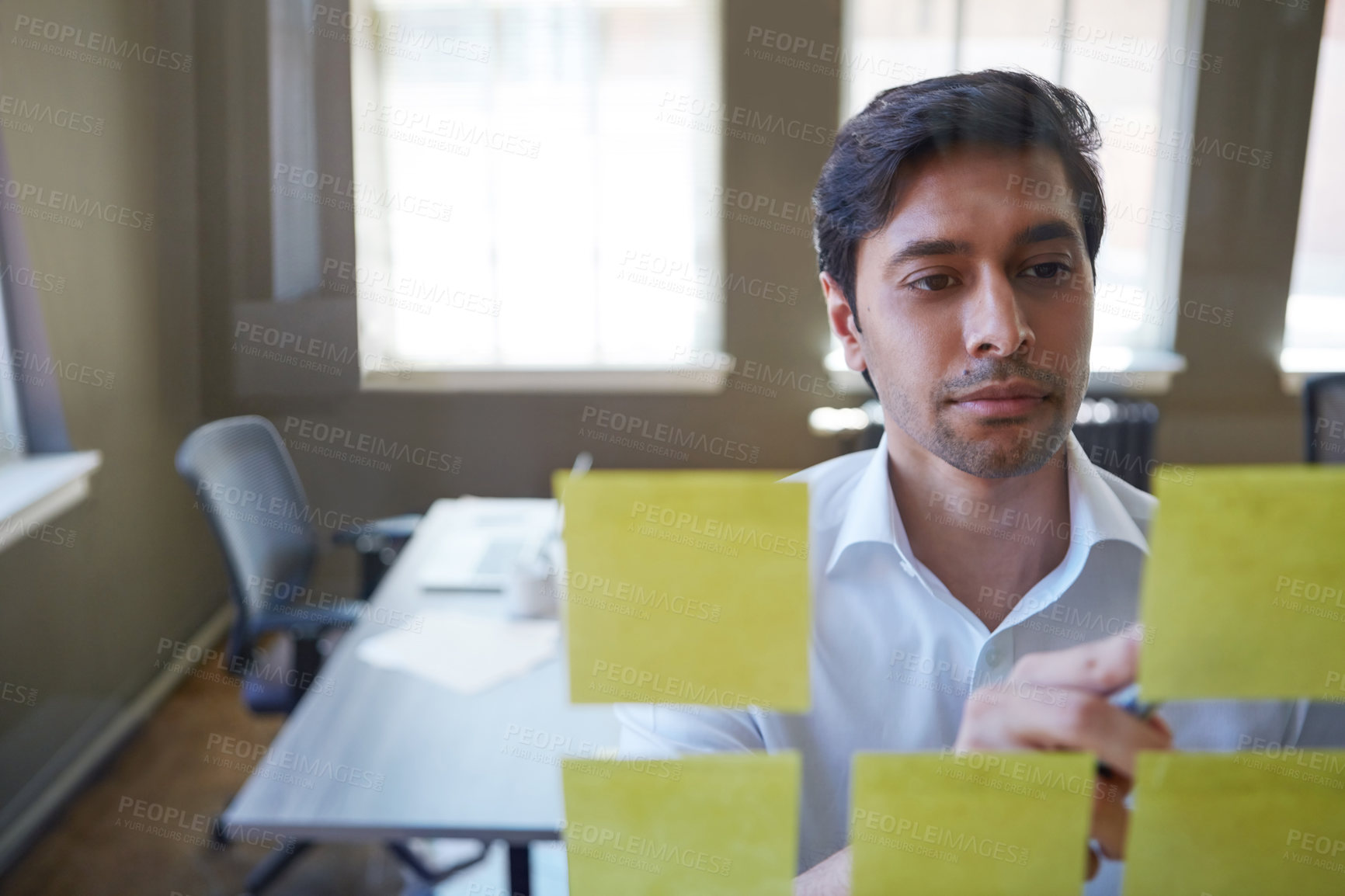 Buy stock photo Cropped shot of a handsome businessman arranging adhesive notes on a glass pane