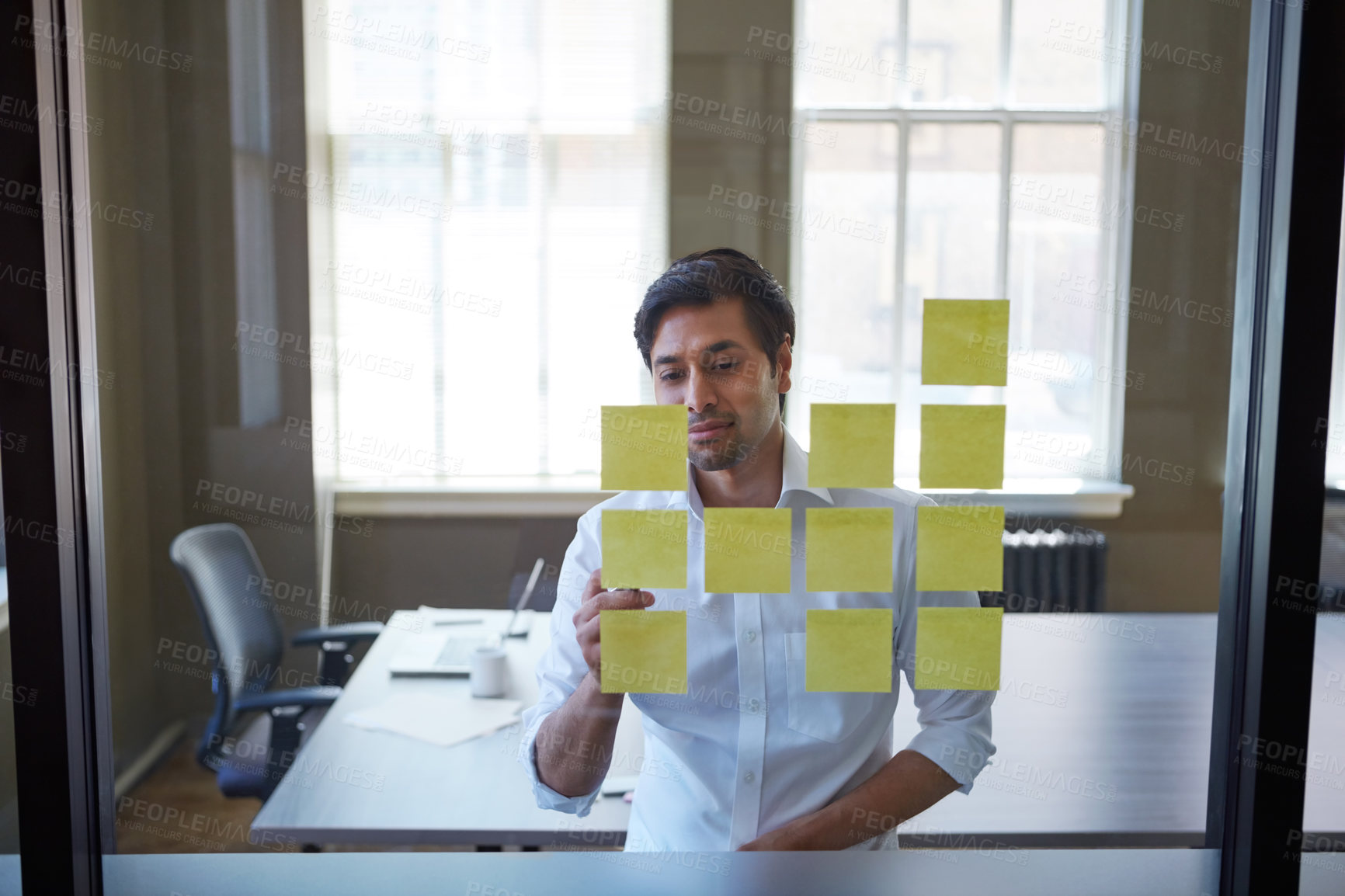 Buy stock photo Cropped shot of a handsome businessman arranging adhesive notes on a glass pane