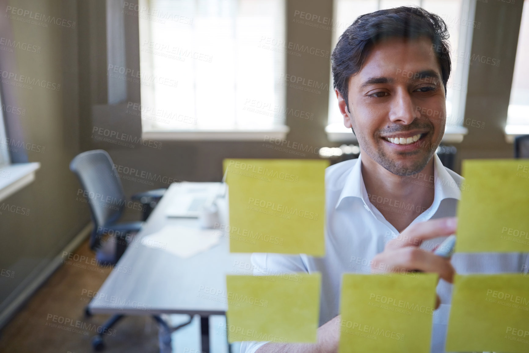 Buy stock photo Cropped shot of a handsome businessman arranging adhesive notes on a glass pane