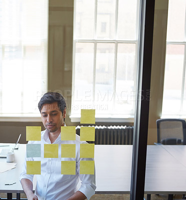 Buy stock photo Cropped shot of a handsome middle eastern businessman arranging adhesive notes on a glass pane