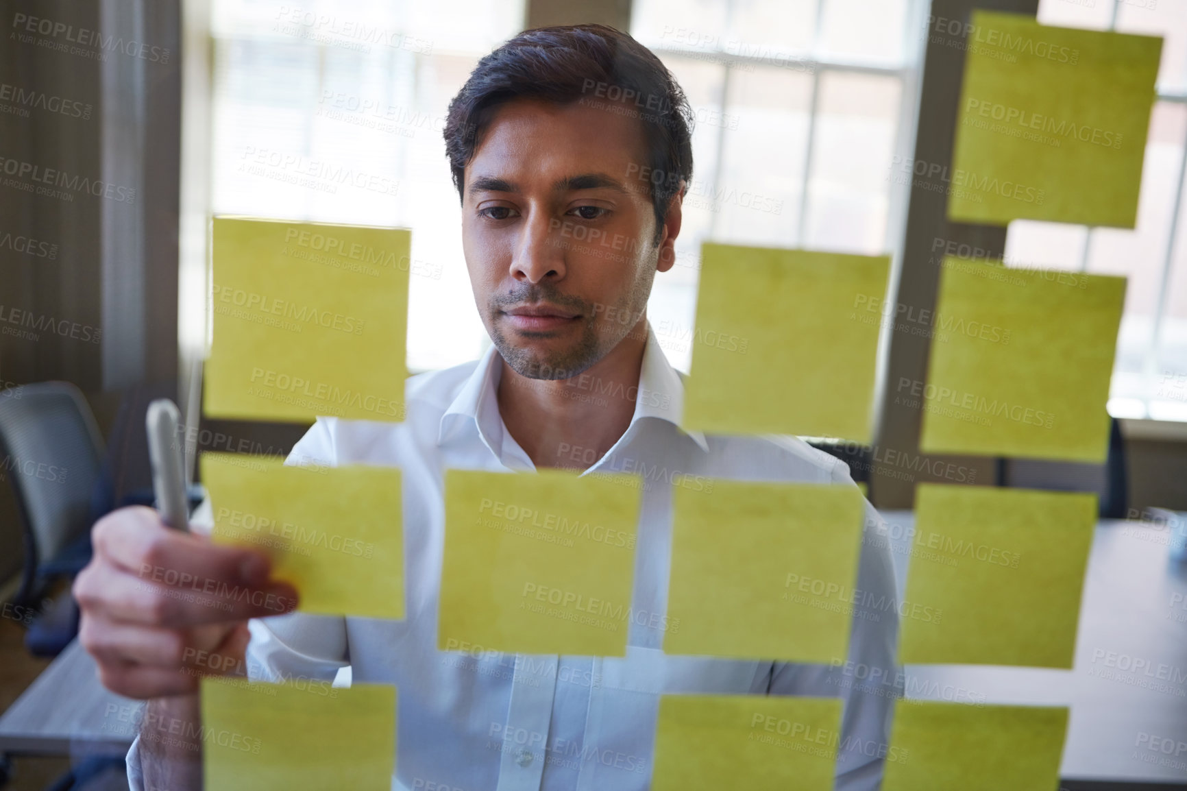 Buy stock photo Cropped shot of a handsome middle eastern businessman arranging adhesive notes on a glass pane