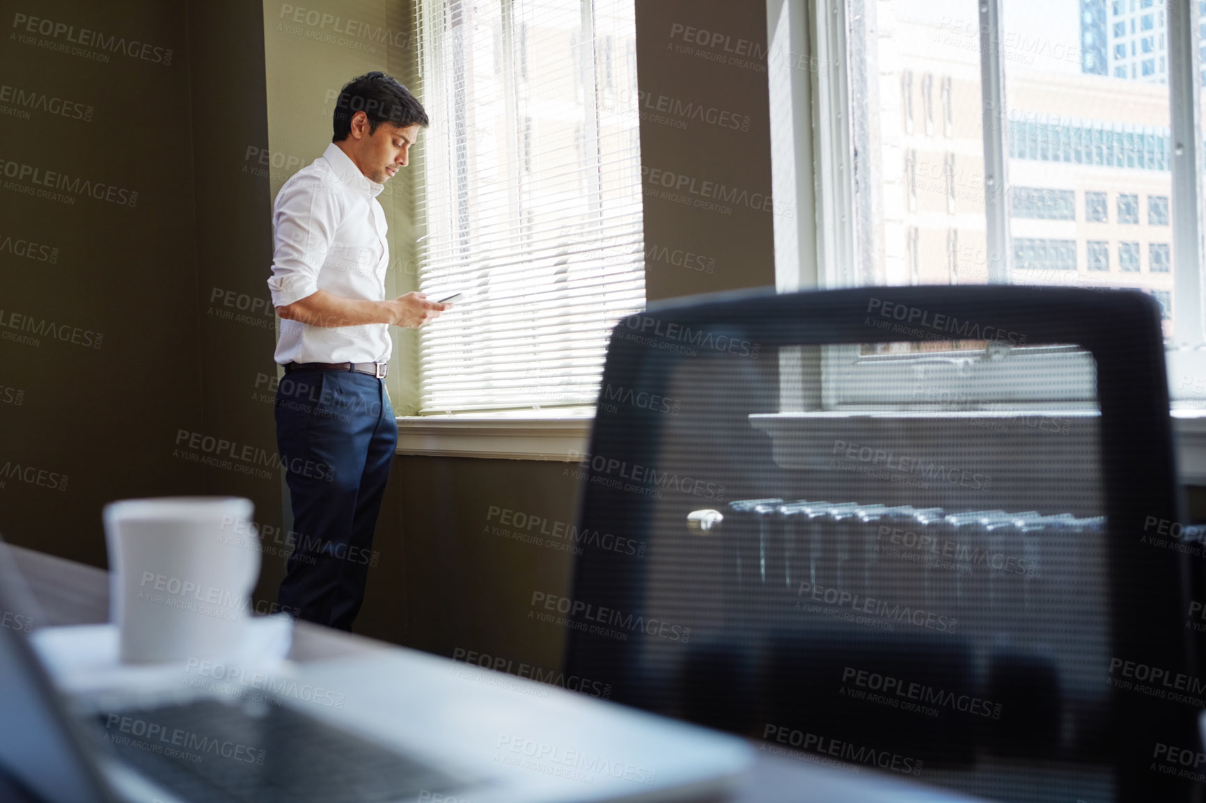 Buy stock photo Shot of a businessman working on his smartphone in the office