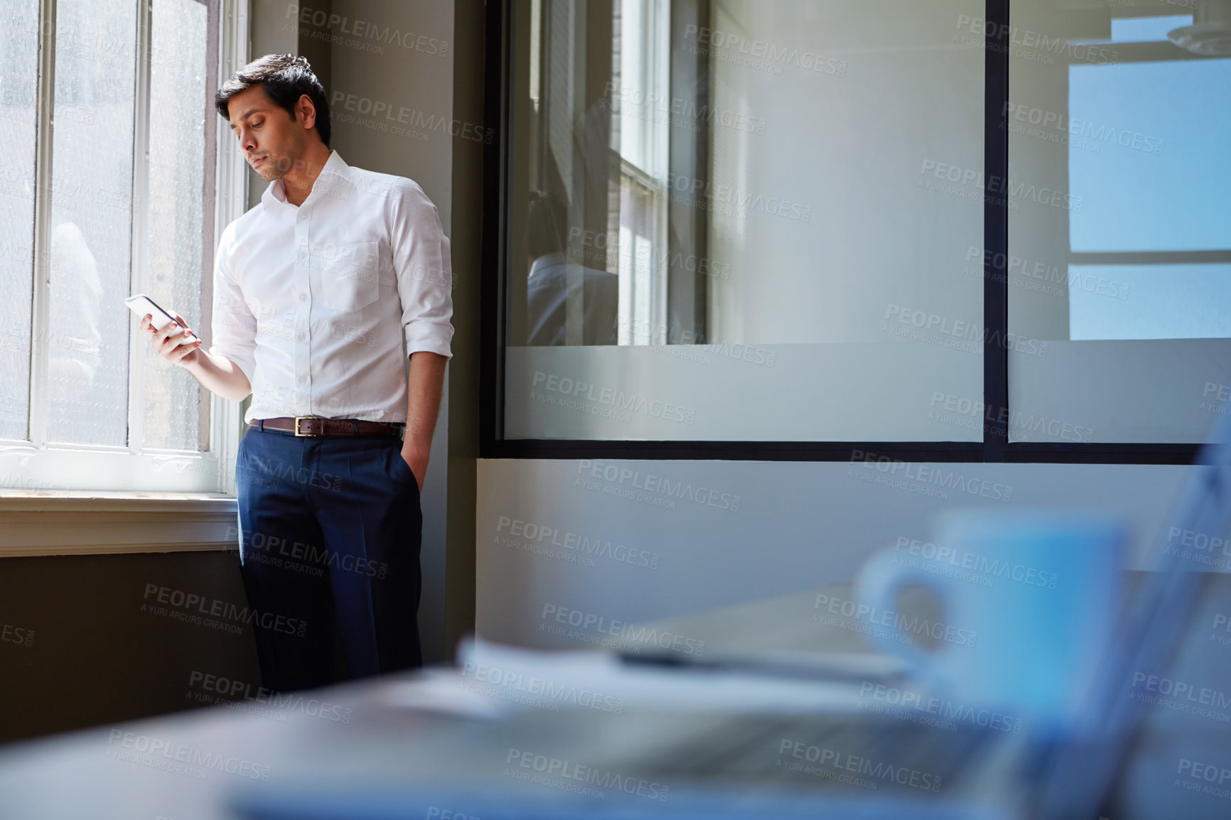 Buy stock photo Shot of a businessman working on his smartphone in the office