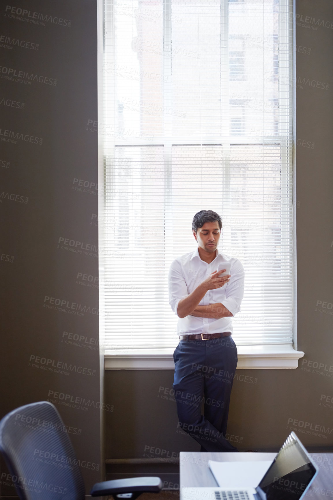 Buy stock photo Shot of a businessman working on his smartphone in the office