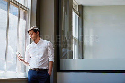 Buy stock photo Shot of a businessman working on his smartphone in the office