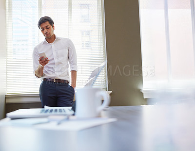 Buy stock photo Shot of a businessman working on his smartphone in the office