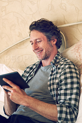 Buy stock photo Cropped shot of a man working on his tablet in bed