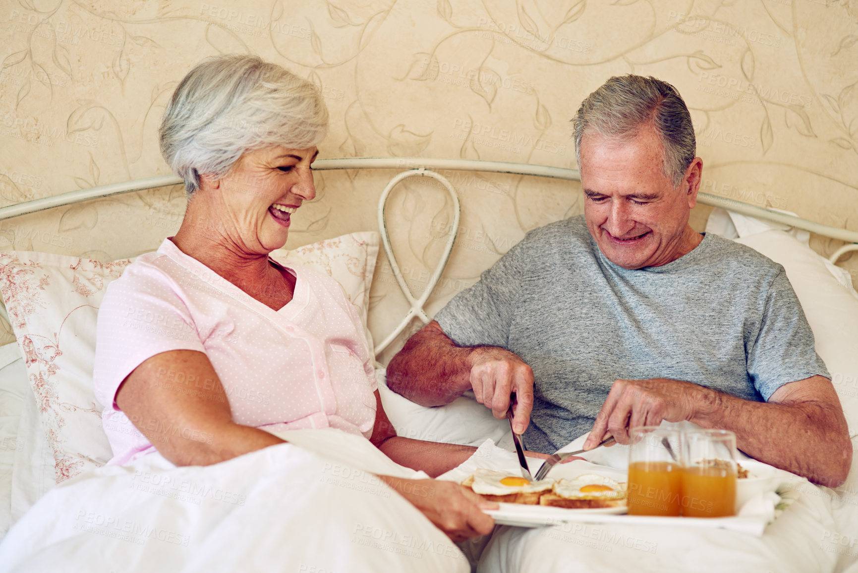 Buy stock photo Cropped shot of a senior couple having breakfast in bed together