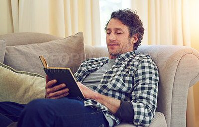 Buy stock photo Cropped shot of a man reading a book on the couch