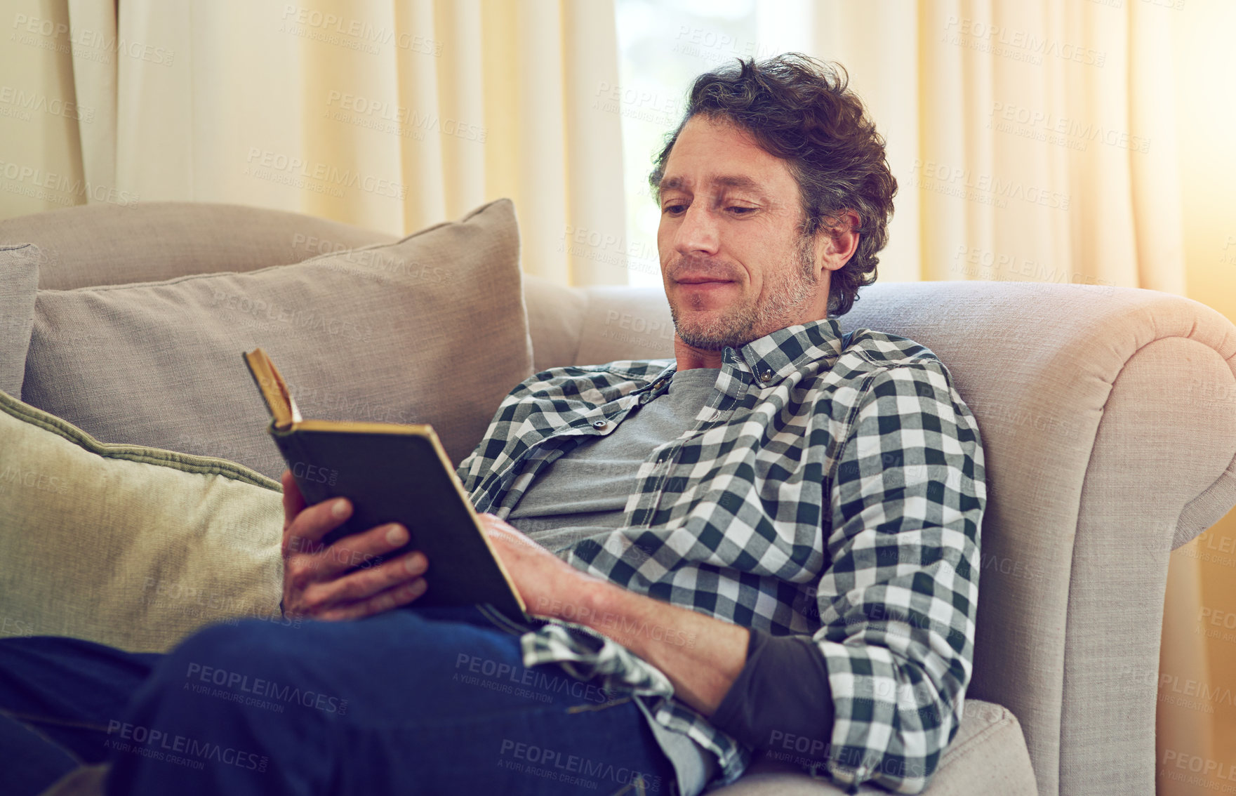 Buy stock photo Cropped shot of a man reading a book on the couch
