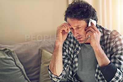 Buy stock photo Shot of a man talking on his cellphone in his lounge