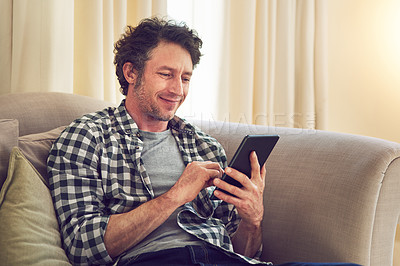 Buy stock photo Shot of a man working on his tablet on the couch