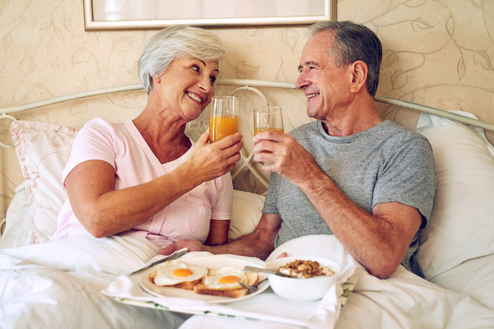 Buy stock photo Cropped shot of a senior couple having breakfast in bed together